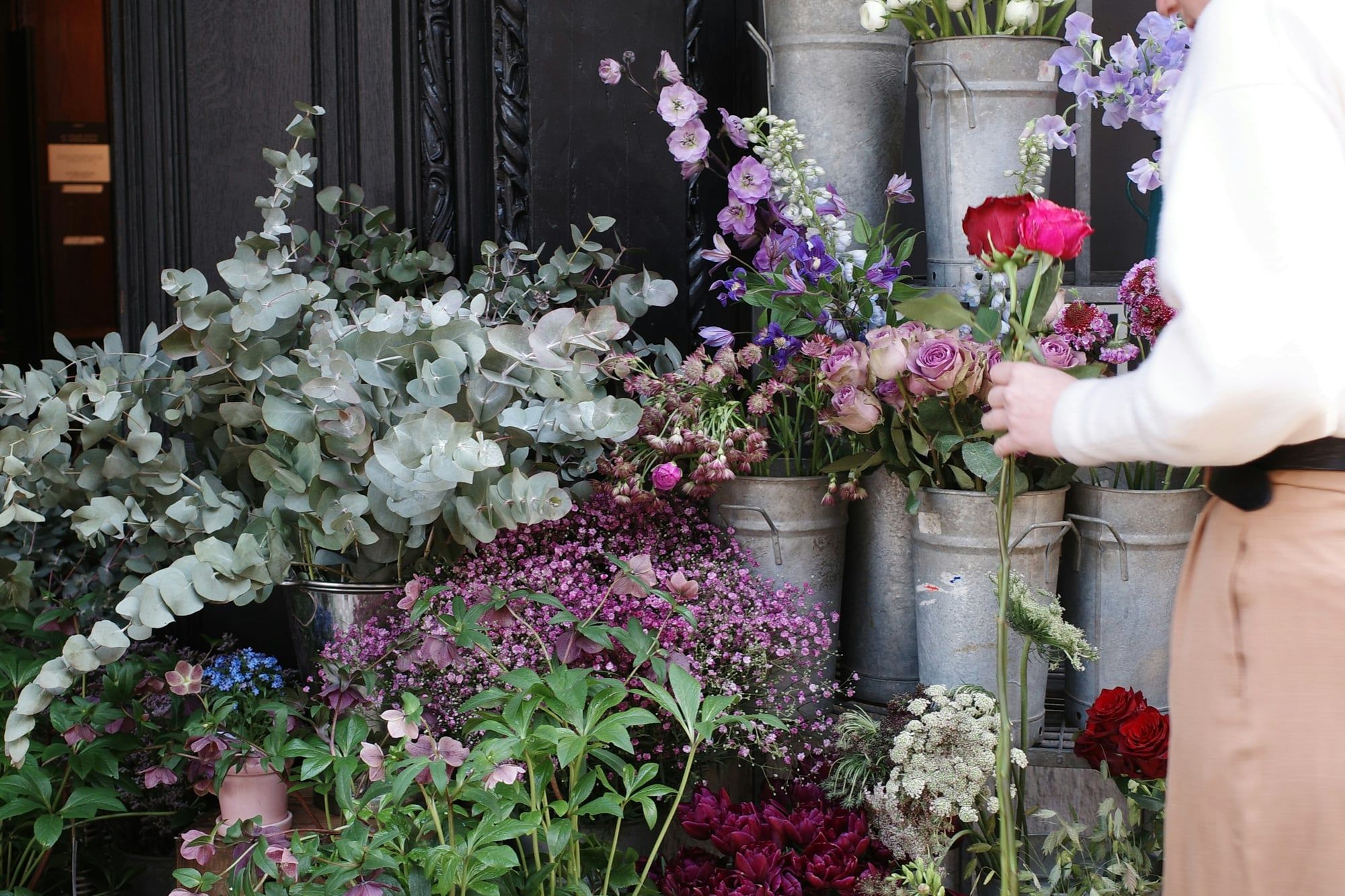 A florist picks roses from buckets of fresh flowers at the shop door